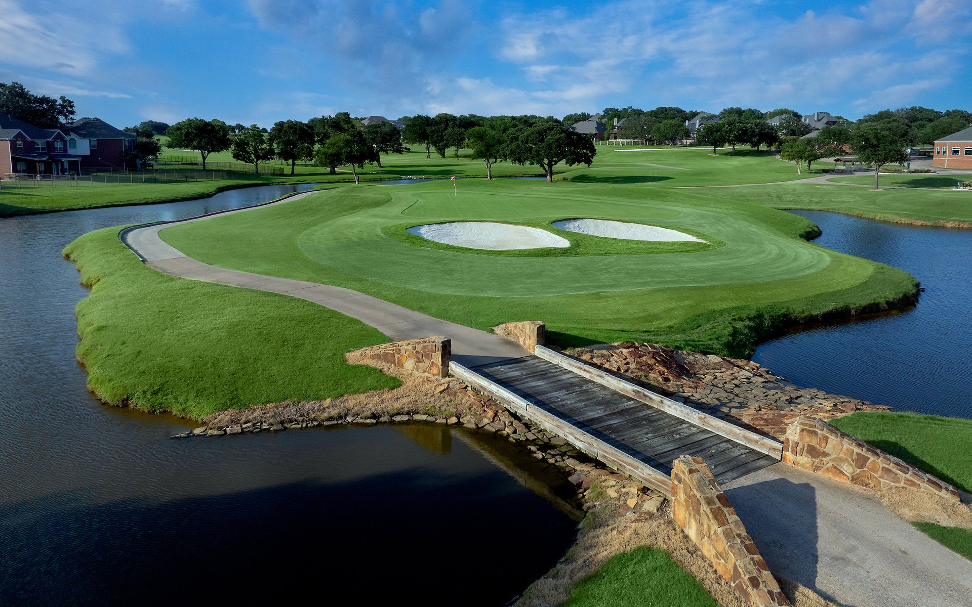Drone aerial of green with bunker, water hazard, and stone bridge